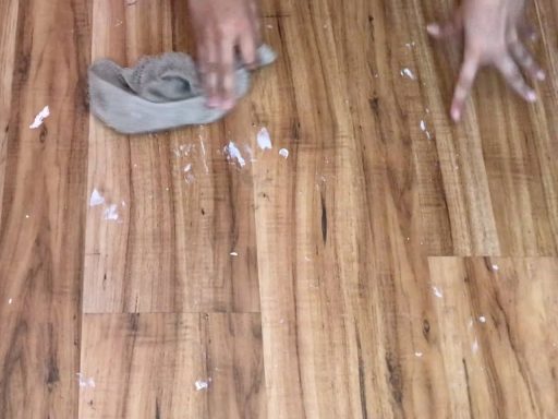 Cleaning paint off hardwood floors with a cloth during the paint removal process