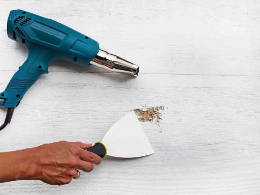 Removing paint from hardwood floors with a heat gun and scraper during the paint removal process