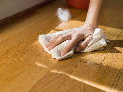 Cleaning unfinished wood floor by hand with a soft cloth during gentle surface care and maintenance