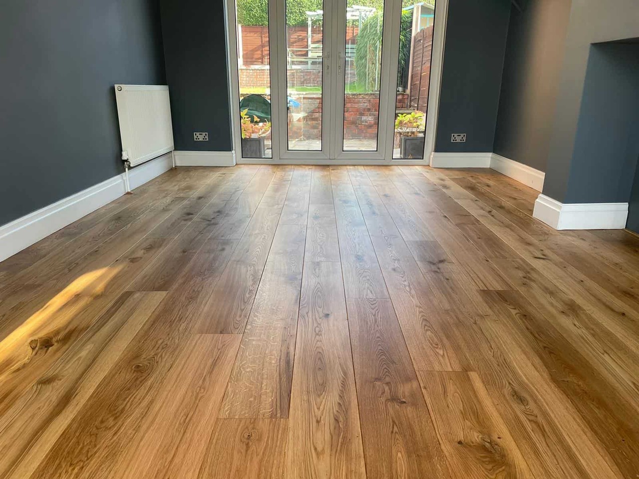 Hardwood floor after sanding and cleanup showing a clean dust-controlled refinishing result in a finished room