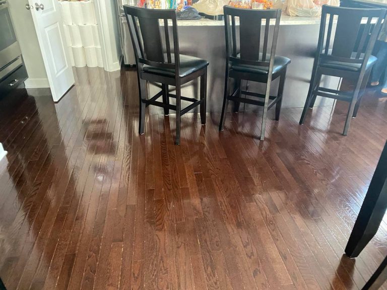 Refinished hardwood floor in kitchen showing a renewed dark finish after professional restoration