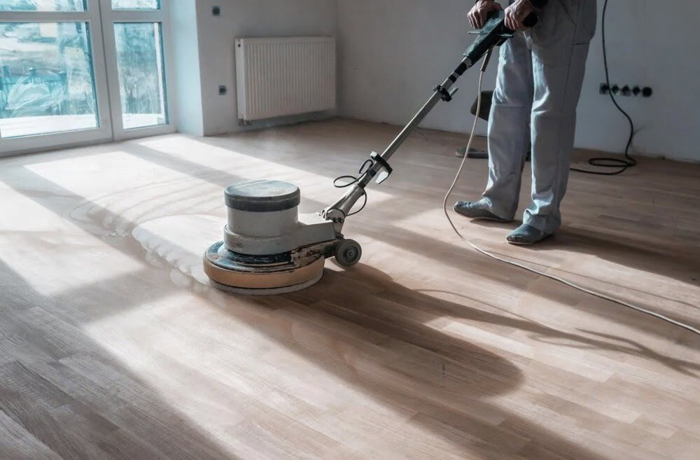 Hardwood floor buffing during home refinishing showing a floor restoration step that can be done while the homeowner remains in the house