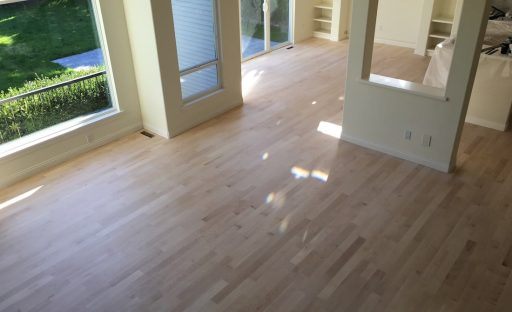 Large room with hardwood floors prepared for refinishing as part of a full home floor restoration project