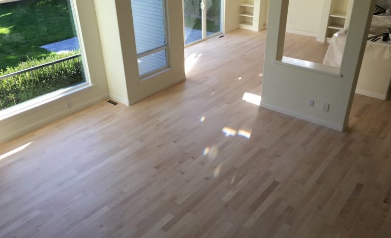 Large room with hardwood floors prepared for refinishing as part of a full home floor restoration project