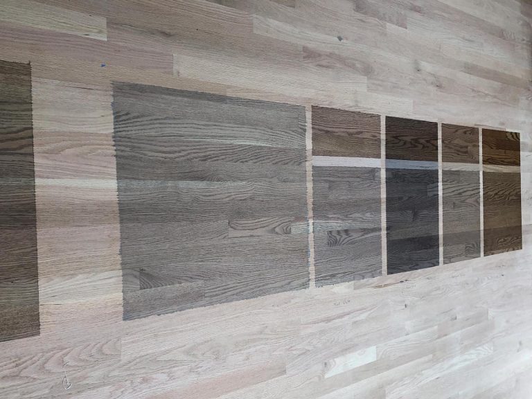 Testing stain colors on hardwood floor to compare tone depth and grain appearance before application
