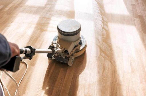 Professional hardwood floor refinishing with floor buffer during final polishing step of the hardwood floor refinishing process
