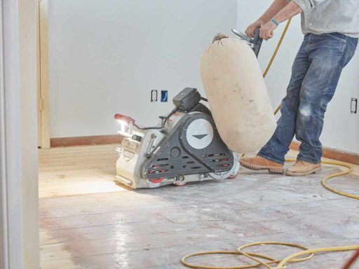 Professional hardwood floor sanding machine removing old finish during a full refinishing process