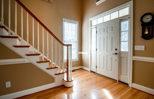 Refinished hardwood floors in home entryway with staircase, showing clean sanded wood flooring after the hardwood floor refinishing process